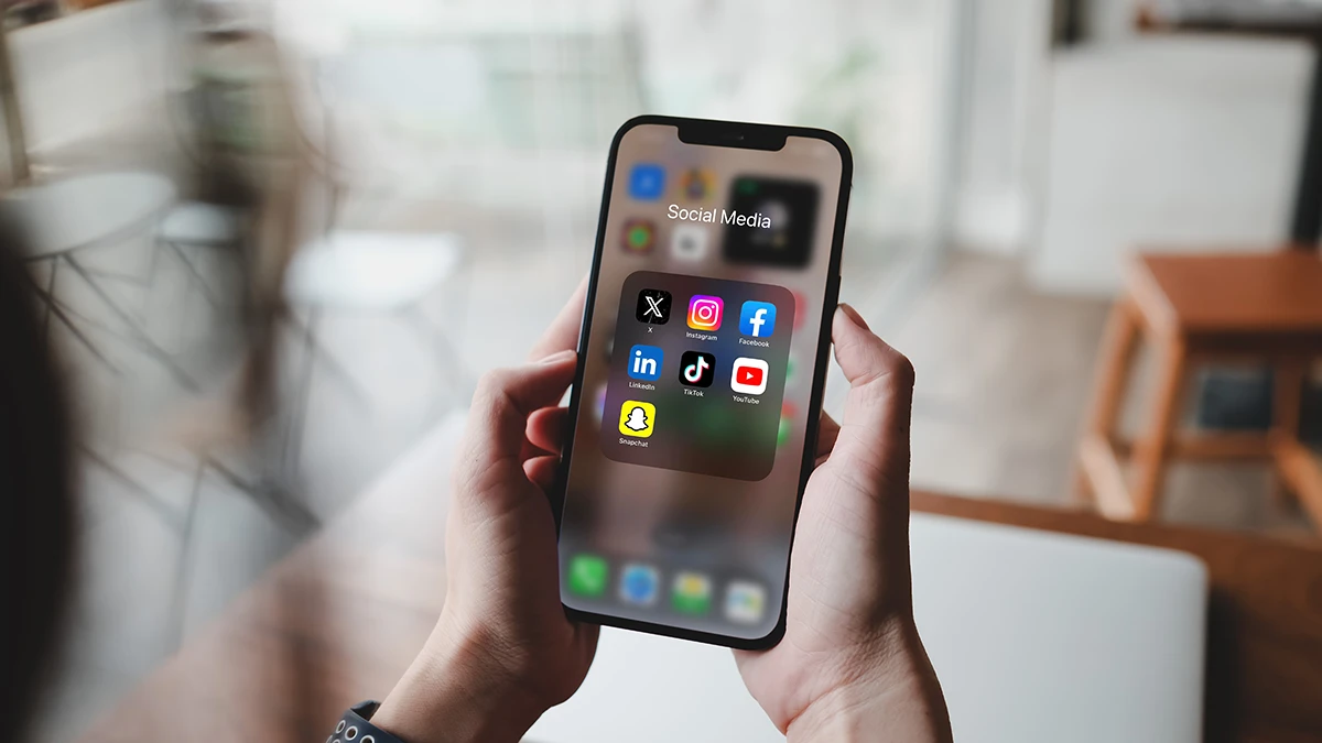 Woman holding a phone showing social media icons.